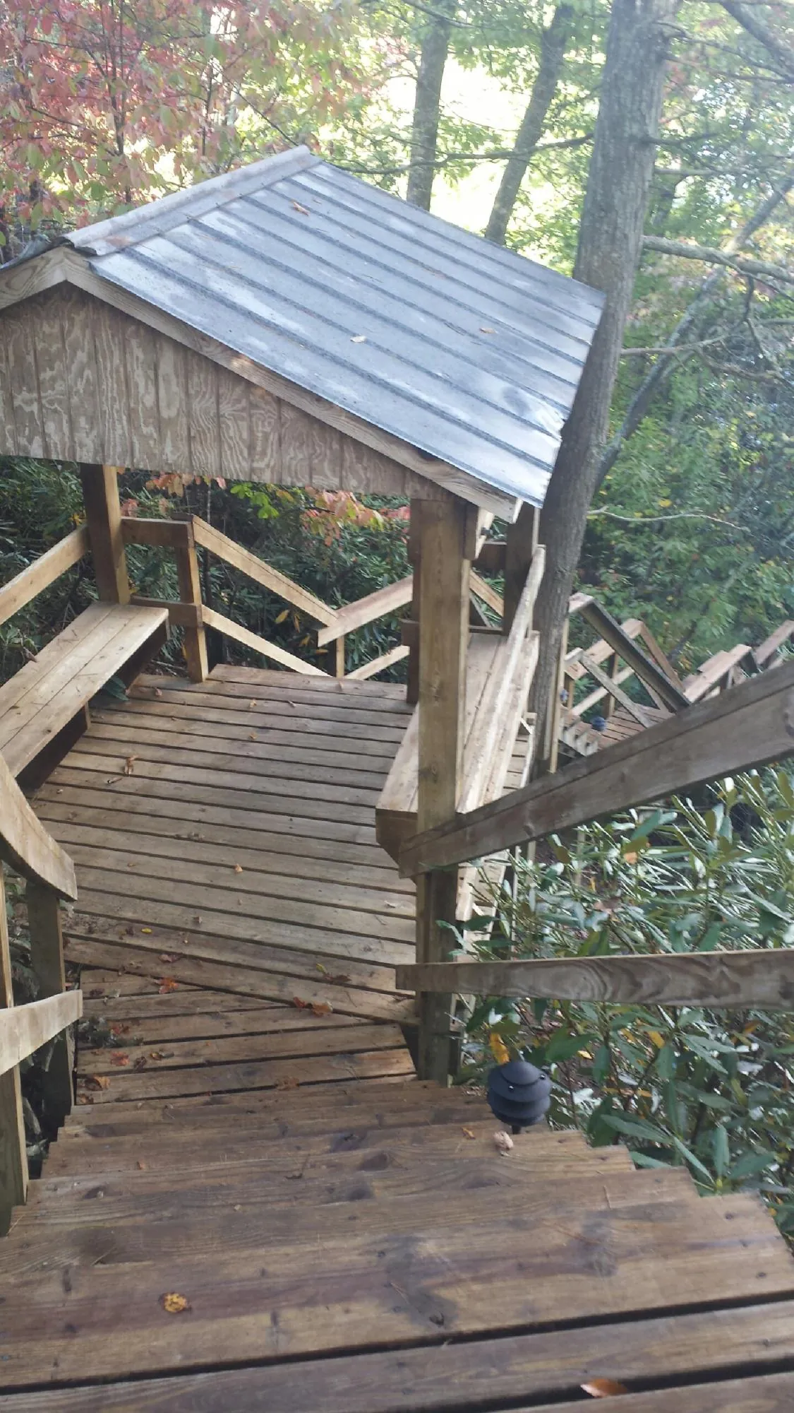 Metal roofed shelter over wooden steps on a wooded walkway — Skylight Repair & Installation work by our crew in Penfield