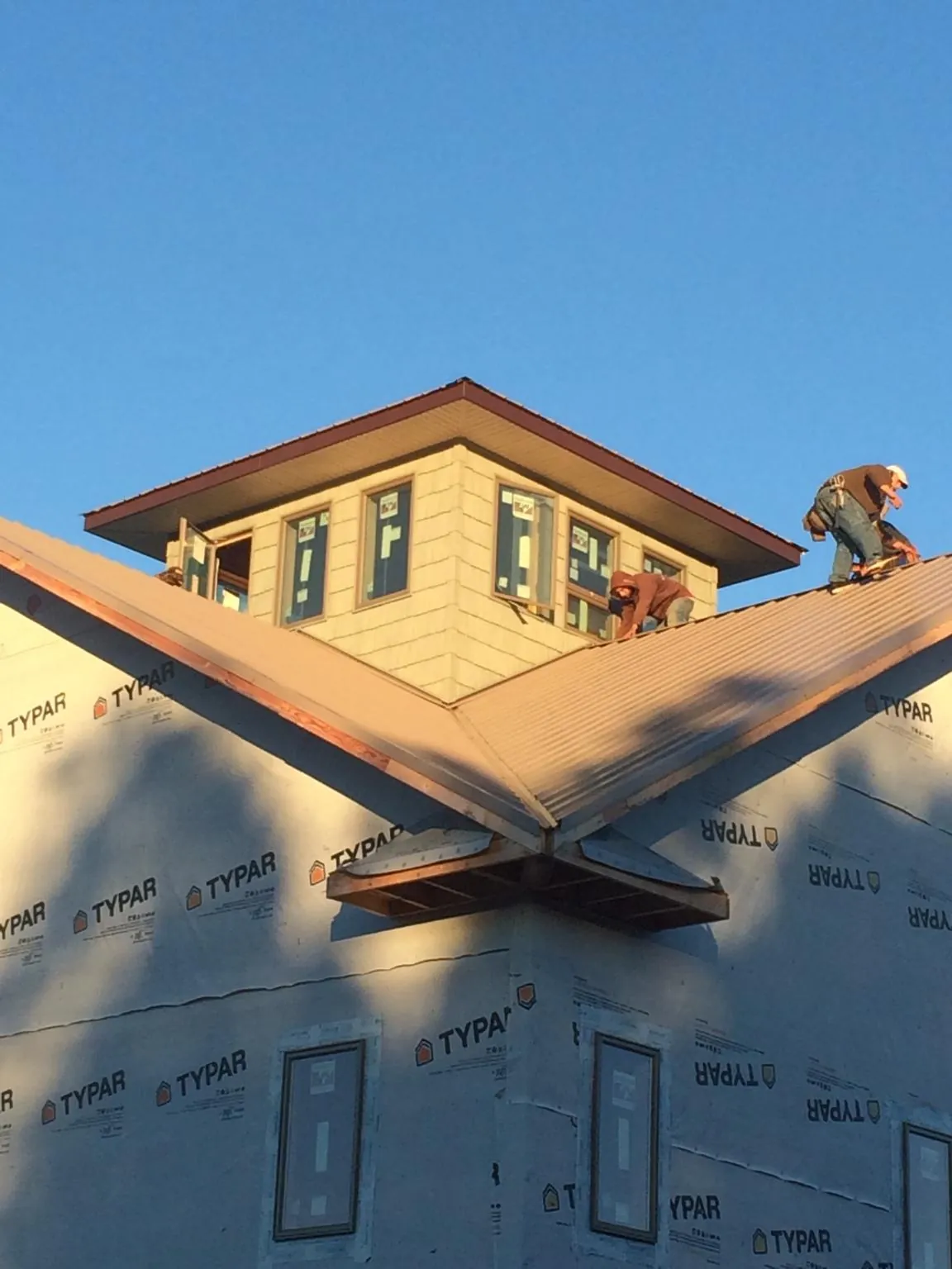 Roofers working around a rooftop cupola on a new metal roof at sunset — Roof Waterproofing in Penfield by Roofing Brothers